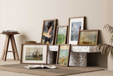 framed artwork including portraits and landscapes displayed on a beige wall